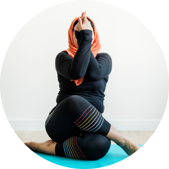 A woman performing yoga asana with crossed legs and twisted hands
